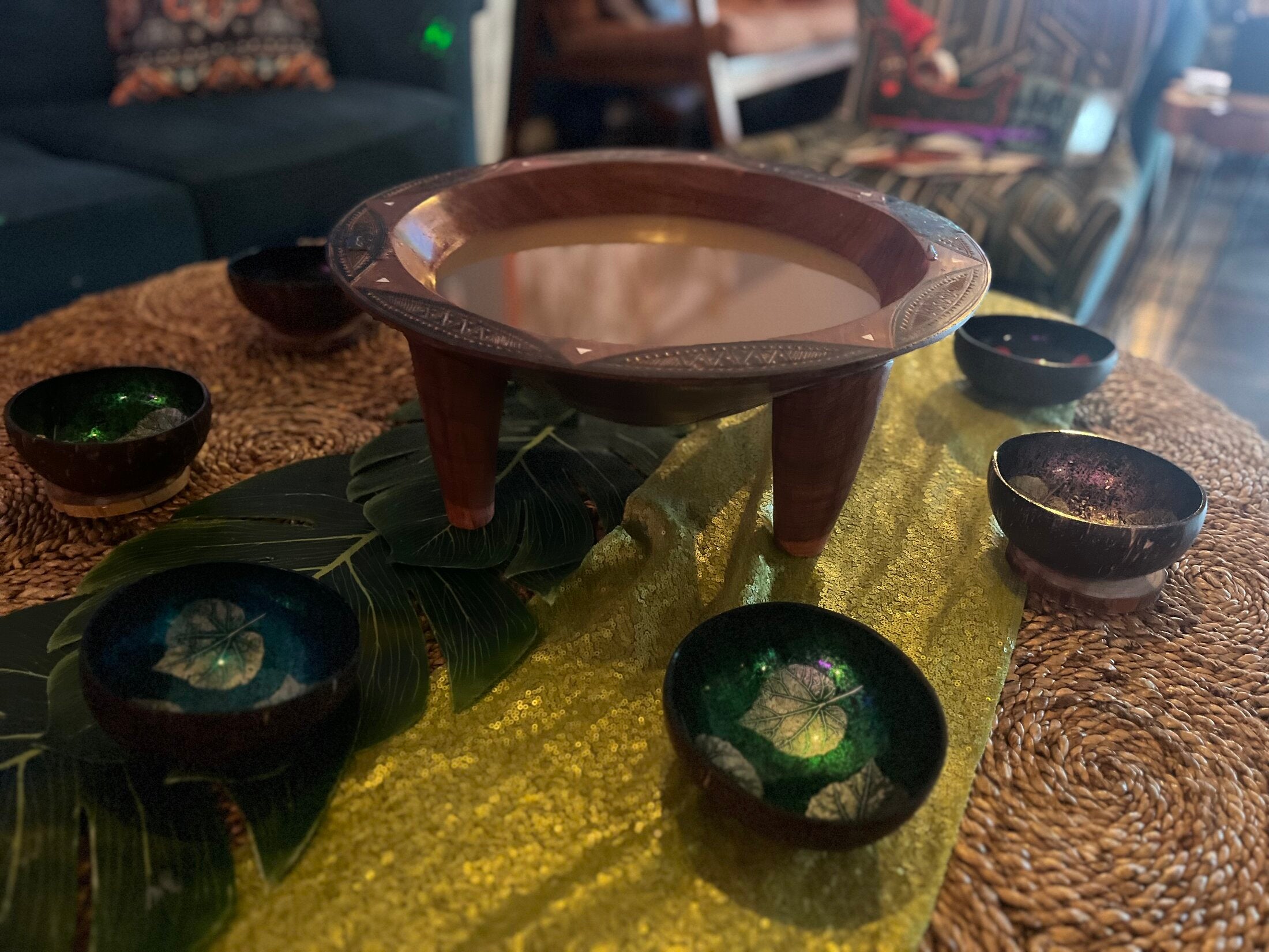 Carved kava tanoa bowl on a stand with decorated coconut shell cups set out in the Elixir Lounge seating area.
