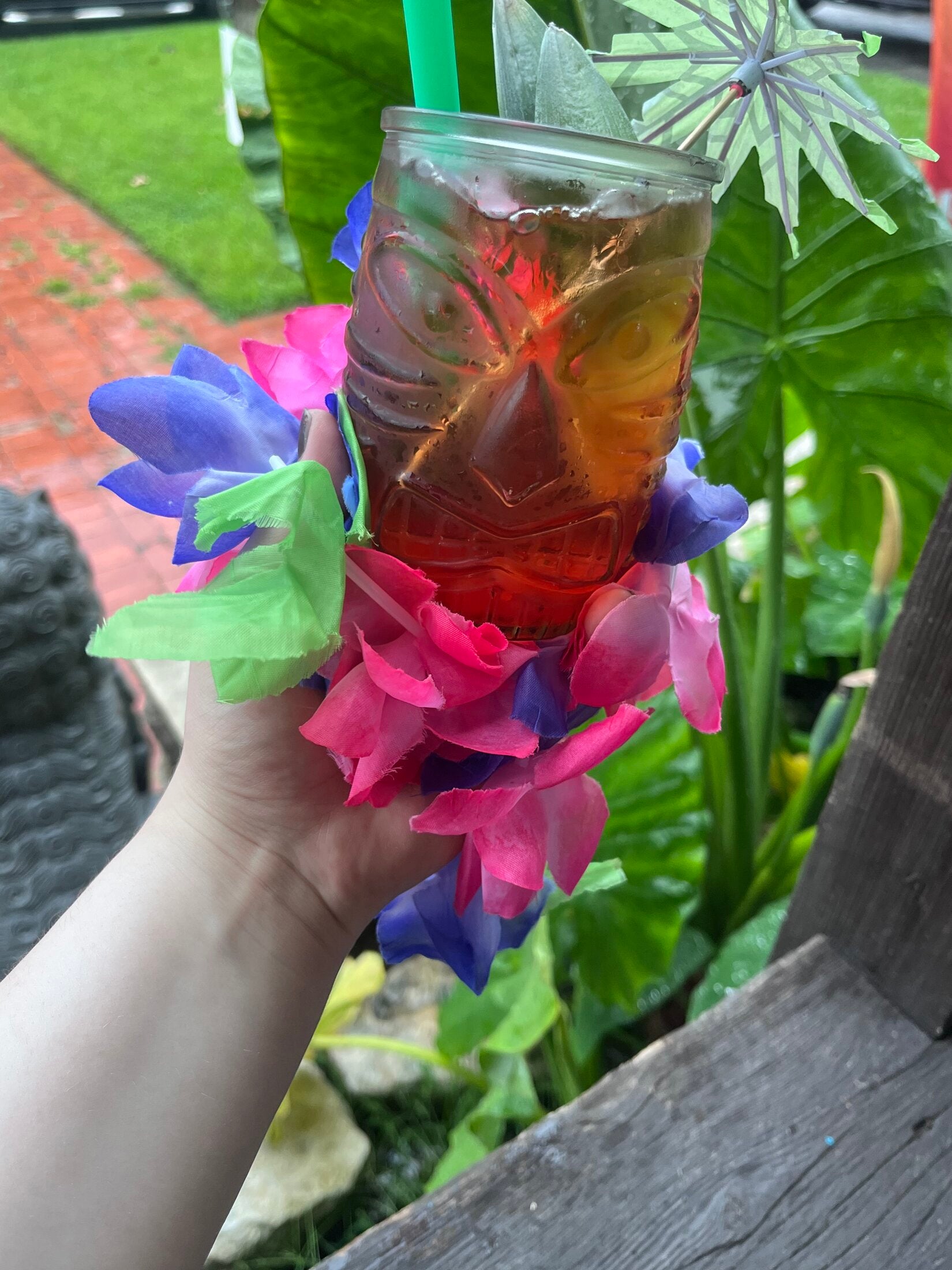 Tiki-face mug cocktail with flower lei and paper umbrella on the Elixir Lounge patio.
